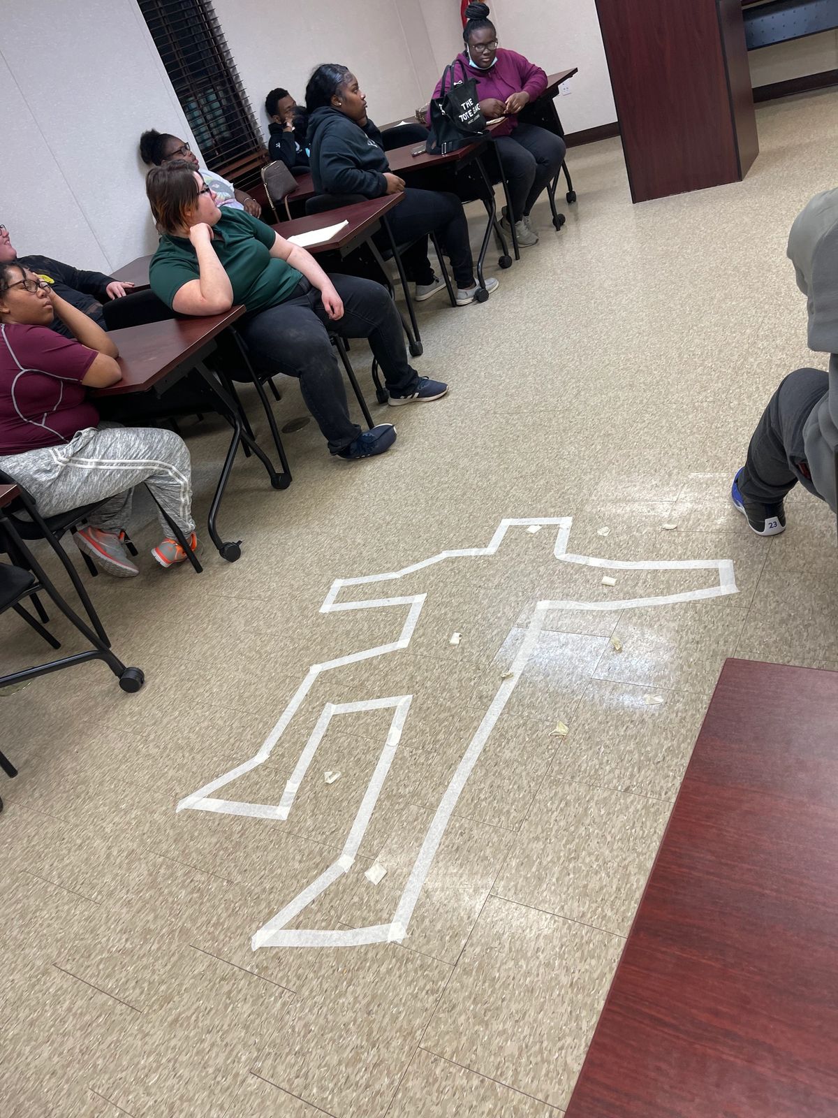 Explorers study a mock crime-scene outline during an investigations exercise.