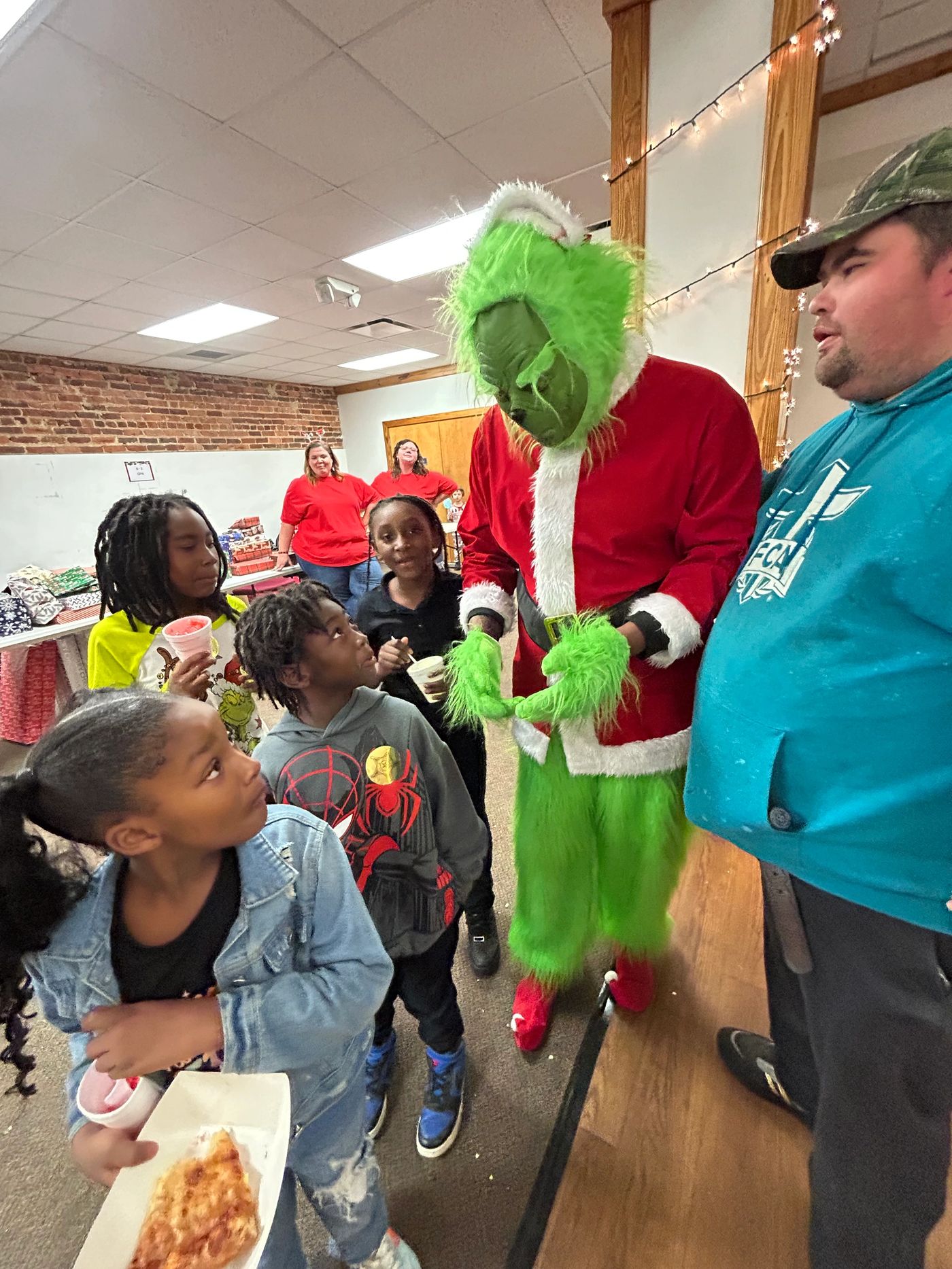 Children greeting the Grinch in a Santa suit during the Santa's Wonderland celebration.